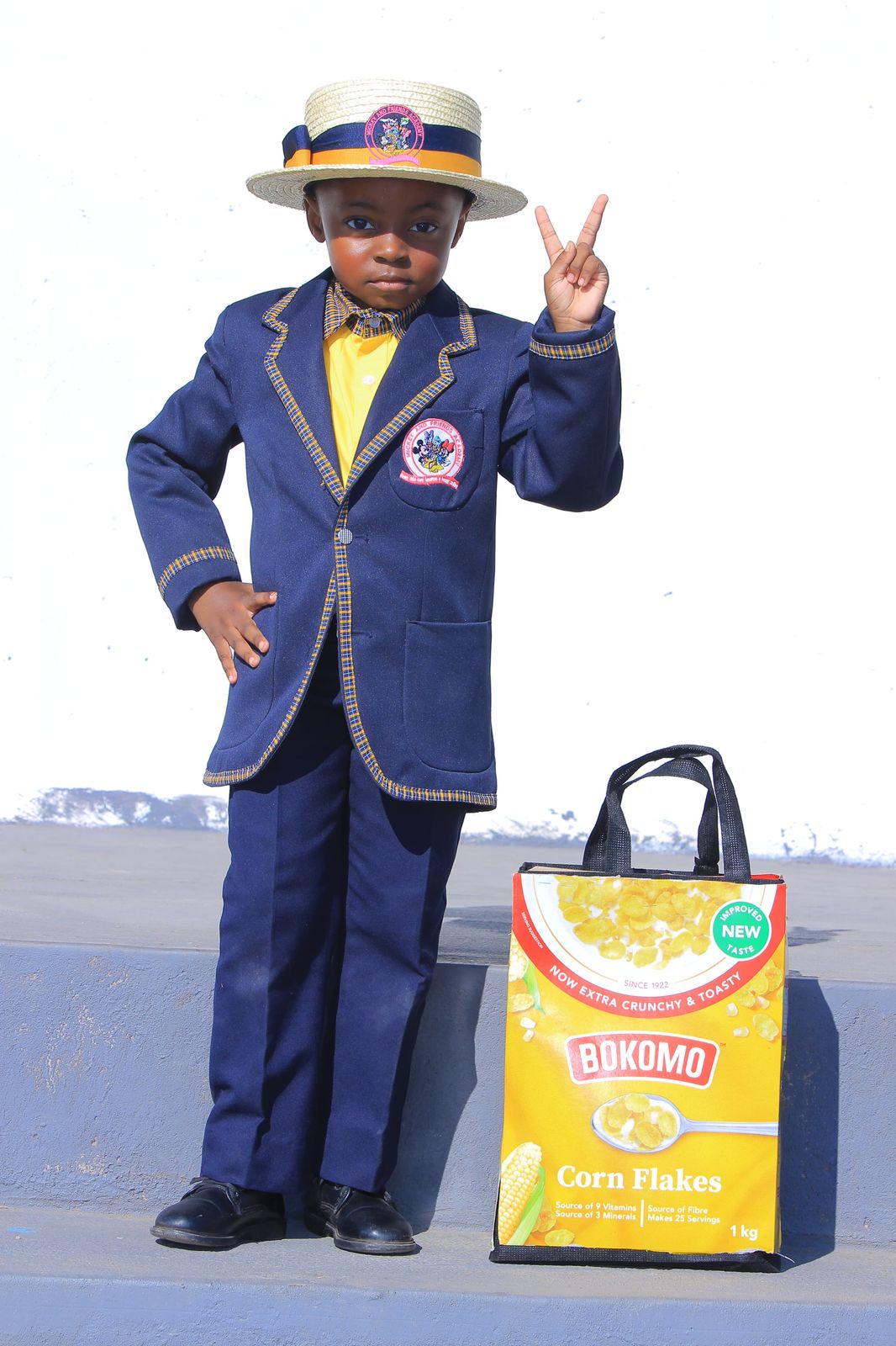 Boy in blazer and boater hat with a cereal box tote bag