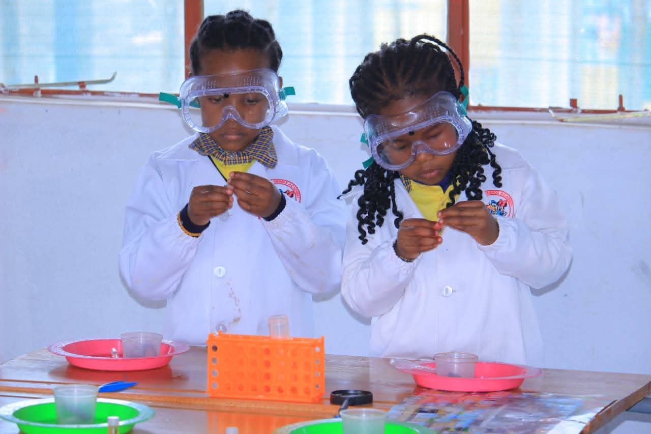 Learners carefully handling small science samples at the lab bench