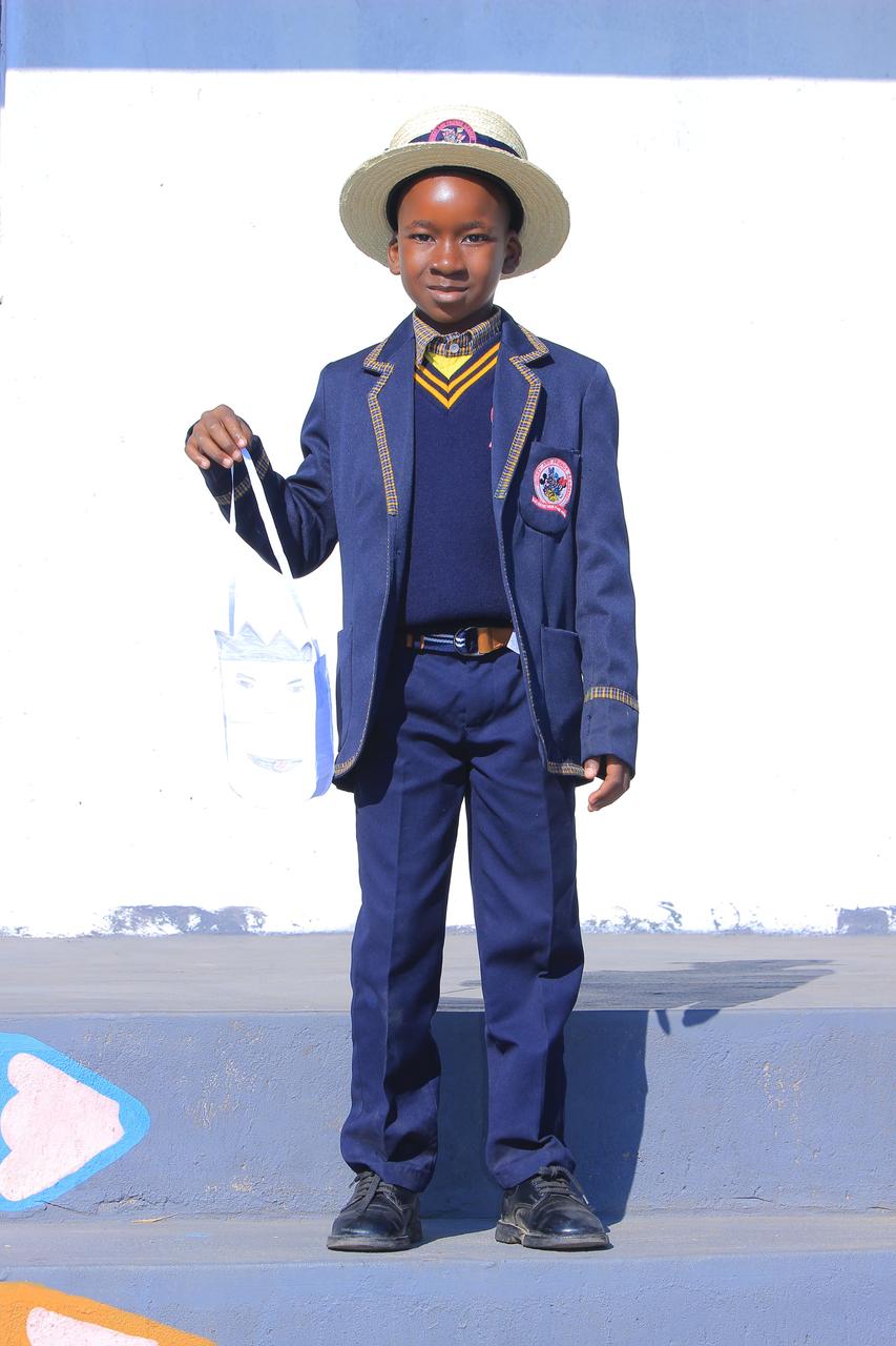 Boy in blazer and hat holding a hand-drawn paper bag