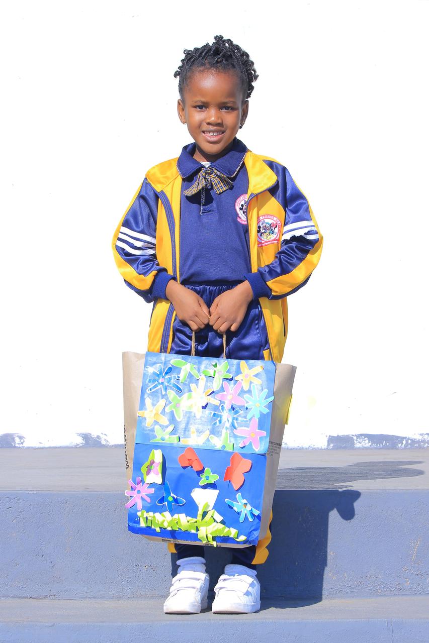 Preschool girl holding a flower-decorated paper bag