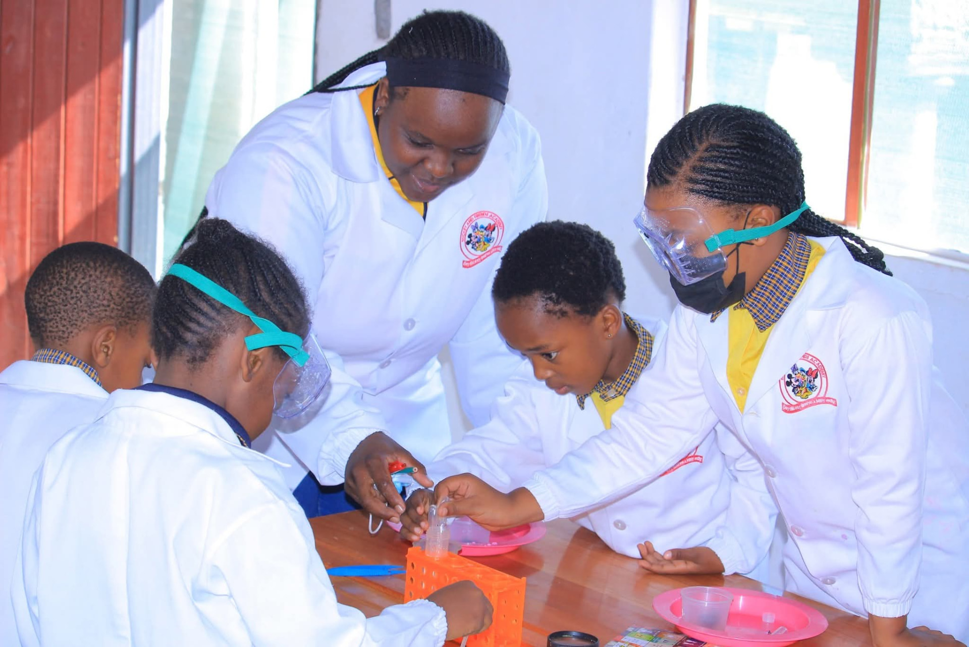 Teacher and learners working with test tubes in the school science lab