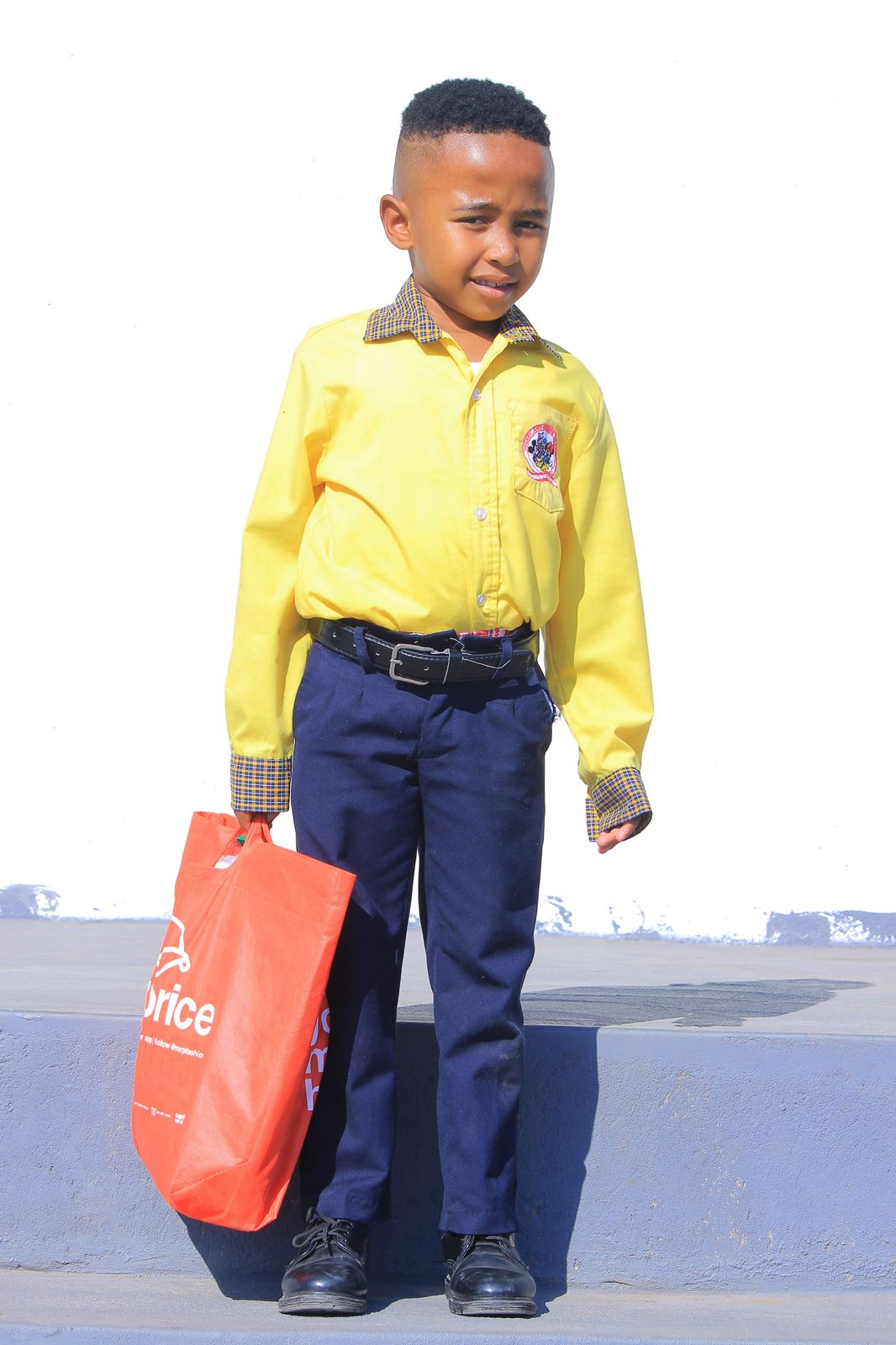 Boy in yellow shirt holding an orange reusable shopping bag