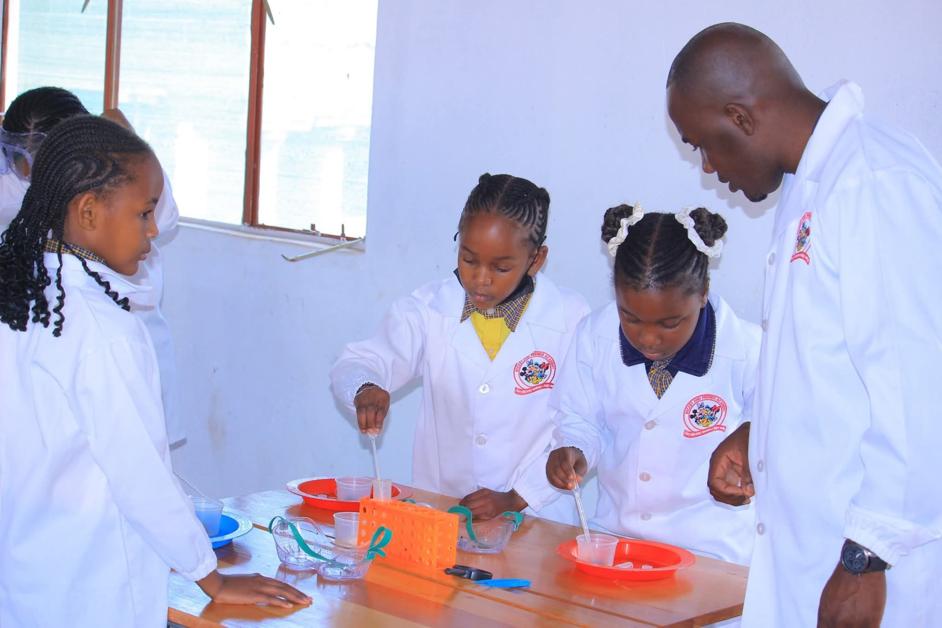 Teacher supervising learners using pipettes in a science practical