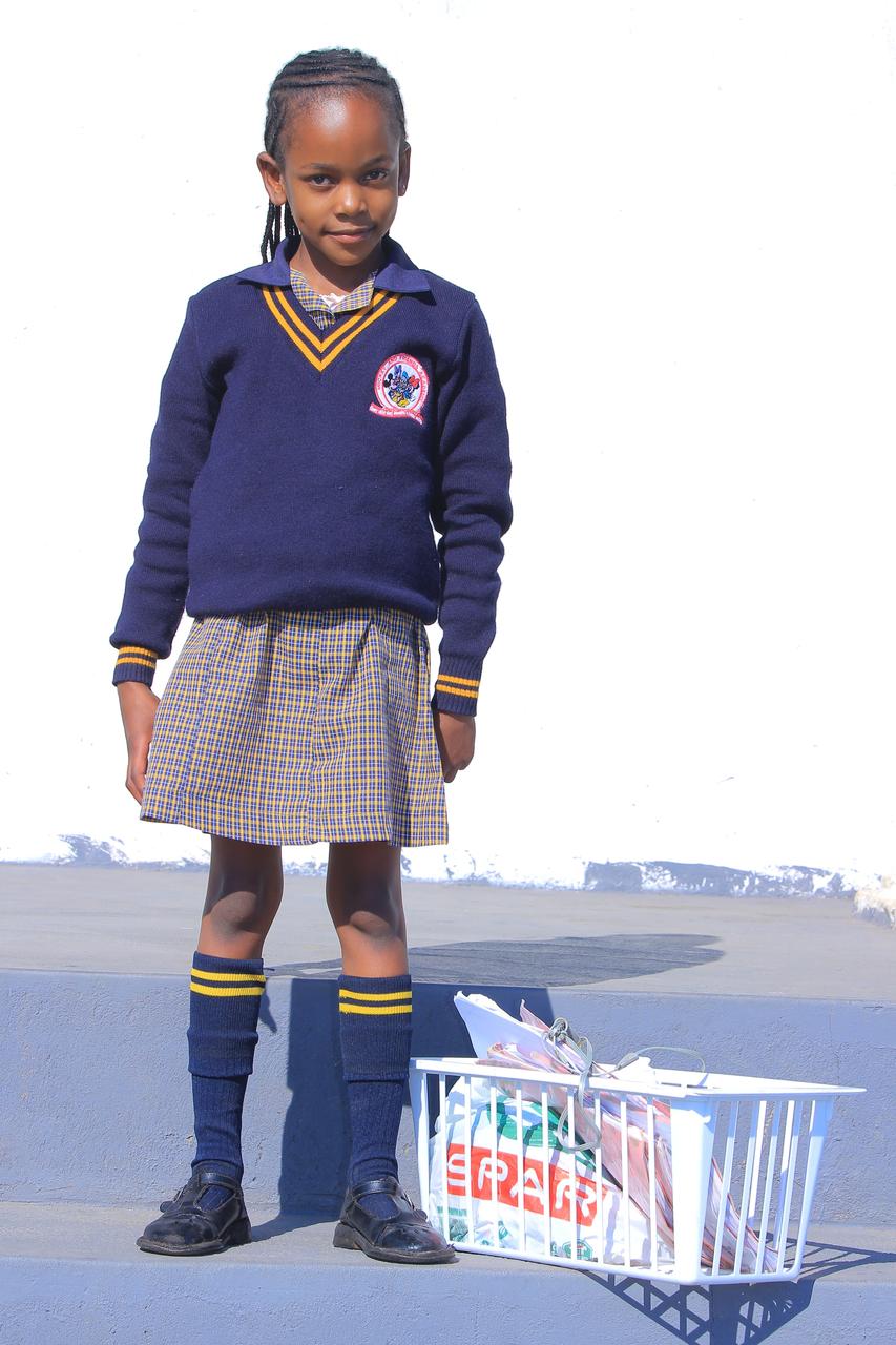 Learner standing beside a basket packed with school books