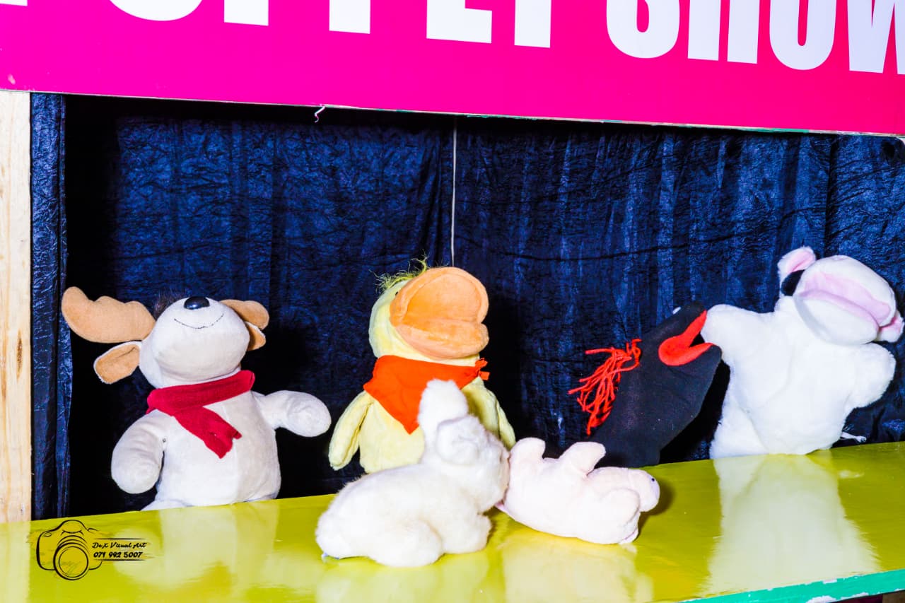Animal hand puppets acting out a story behind the stage curtain