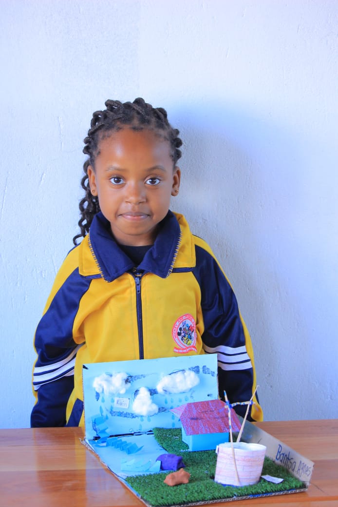 Young learner displaying a rain and well model project