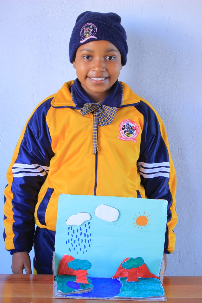 Pupil holding a hand-drawn water cycle poster