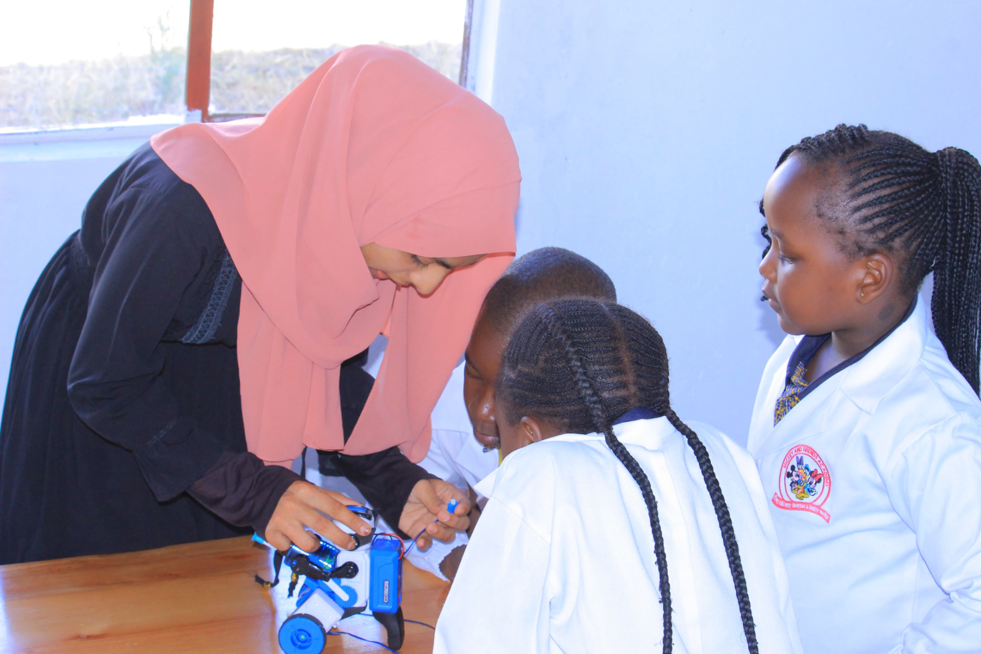 Teacher helping pupils wire a robot car